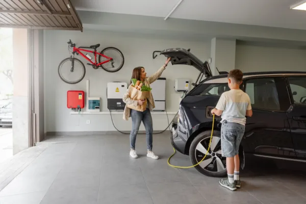 son using ev charger in garage while mother grabs groceries