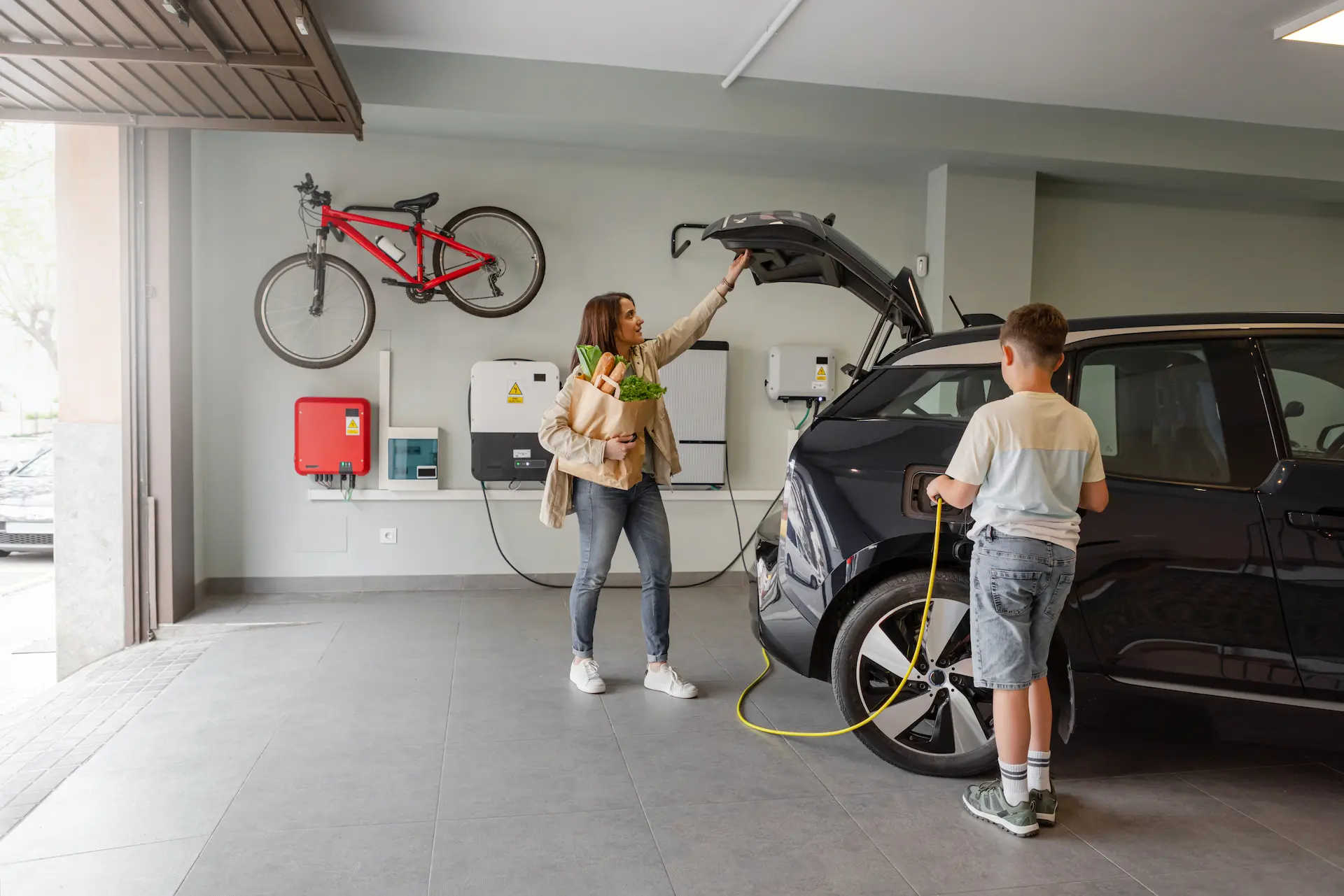 son using ev charger in garage while mother grabs groceries